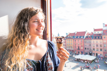 Woman holding one vanilla chocolate ice cream gelato cone with background of Warsaw, Poland old...