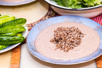 Table with setting of healthy vegan vegetarian lunch or dinner green vegetables cucumbers salad and traditional Russian or Ukrainian buckwheat porridge