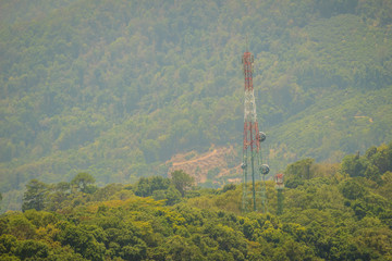 A tall telecommunication tower is standing in amid the green valley background. A telecom tower in a rural area needs off-grid power to transmit cell signals.