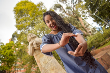 Latina girl shows us the size of something by means of her hands while walking in a park near Marco Polo