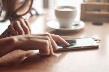 Business woman hands using smart phone and cup of coffee.