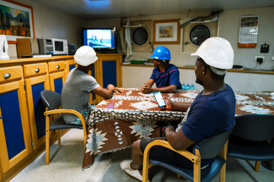 Seamen crew onboard a ship or vessel having fun watching TV. Recreation during at sea