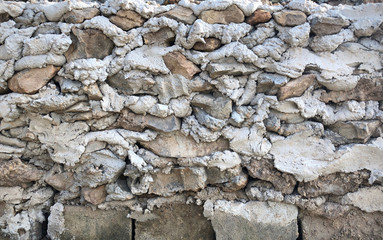 background of dry stacked concrete and rocks in layer design, uneven wall with rough cement and stone in loft style for garden and outdoor decoration