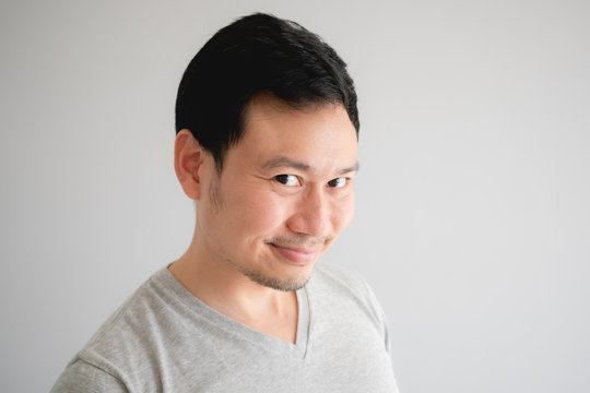 Funny tricky awkward smirk face of man in grey t-shirt.