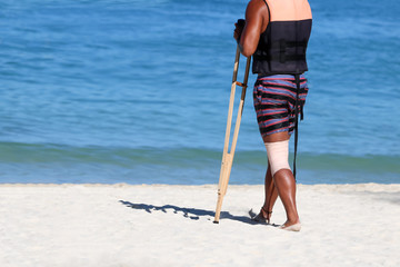 Accident tourist man are walking by crutches on the beach while travel ,