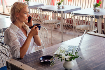 Woman freelance freelancer with laptop on the beach sitting in summer cafe .business lady remote work surfer surfing online browser