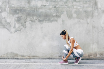 Fitness sport woman in fashion sportswear doing workout over gray wall