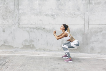 Fitness sport woman in fashion sportswear doing workout over gray wall