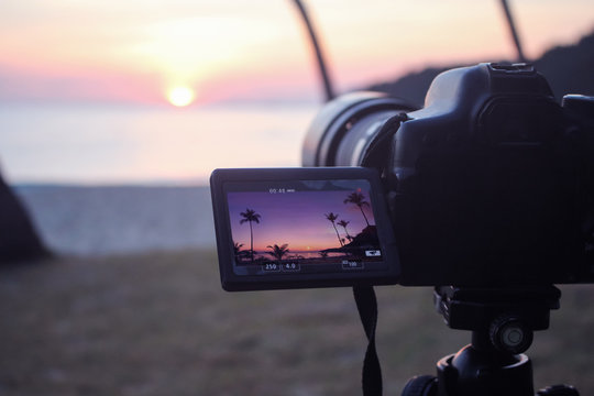 The camera with flip screen  while recording a video view of the sunrise on the beach