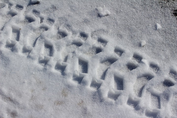 Macro overhead view of tire track imprints on a snowy road surface