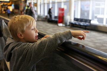 Little Kid on People Mover at Airport Pointing out Window