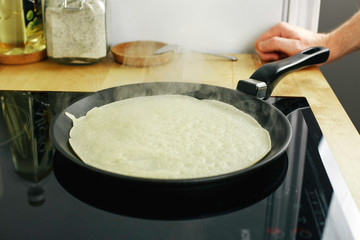 Pancakes are roasted on the stove in a griddle. There is smoke