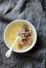 Simple beef broth with beef meat, onion and pepper on grey background, top view. Healthy food, soup base
