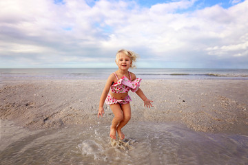 Cute Little Kid Splashing and Playing in the Water on the Beach by the Ocean