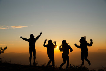 Group of happy young people jumping on the hill. Young women enjoying on their holiday outdoors.