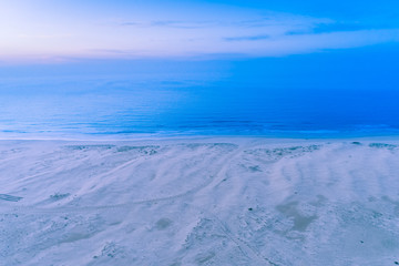 Fototapeta na wymiar Aerial view of ocean coastline at dawn. Nothing but White sand, blue water and sky.
