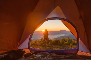 Foto op Plexiglas Wandelaar staan op de camping in de buurt van oranje tent en rugzak in de bergen. Backpacker op zoek in de verte © doidam10