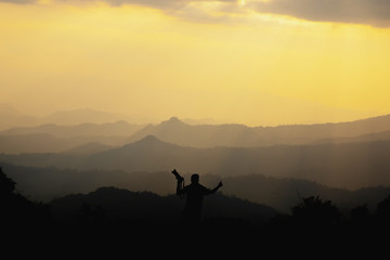 silhouette of a photographer who shoots a sunset in the mountains