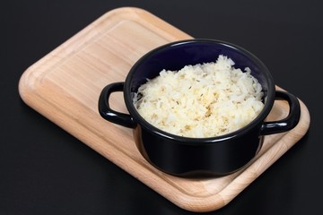 Sauerkraut  in a pot.  Sauerkraut (fermented or pickled cabbage) on a chopping board, black background