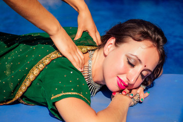 Young beautiful indian woman bindi third eye in green stylish sari having oil Ayurveda spa...