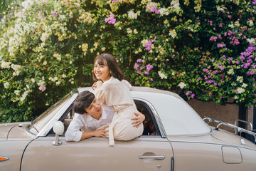 Portrait of hipster couple with classic car. Love on road trip concept.