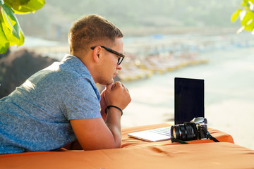 A smiling man with laptop outdoor summer time vacation