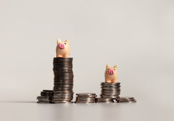Two miniature pink piggy on top of pile of coins.