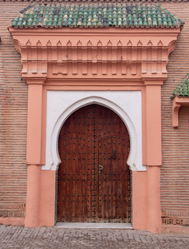 Traditional Moroccan style design of an ancient wooden entry door. In the old Medina of Marrakech, Morocco. Typical, old, brown intricately carved, studded, Moroccan riad door