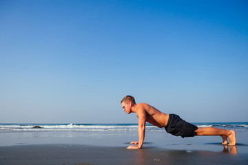 Fototapeta na wymiar Muscular man during workout on the summer beach