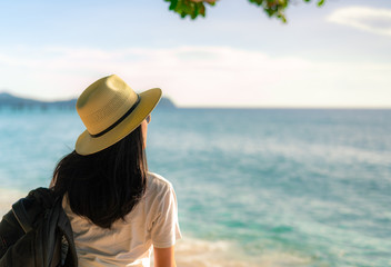 Fototapeta na wymiar Back view of happy young Asian woman in casual style fashion with straw hat and backpack. Relax and enjoy holiday at tropical paradise beach. Summer vibes. Relaxing and enjoying at tropical beach.