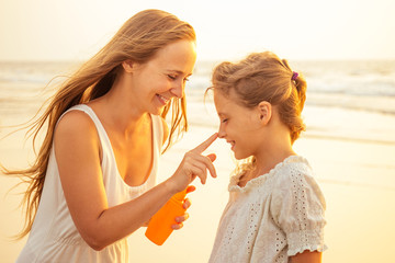 Mother and daughter applying sunscreen on body spf