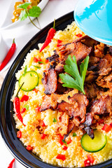 Tajin with couscous, vegetables and meat on white background