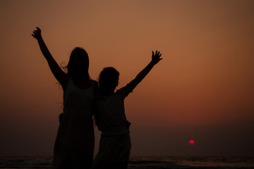 Happy mother and young daughter on the beach at sunset having fun at the seaside. playing jumping and rejoicing woman and her child copy space copyspace