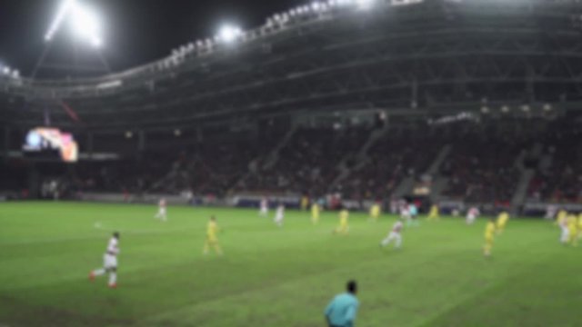 Blurred view of football game at the stadium, view from the stands, man players play football.