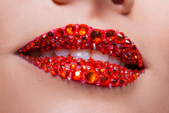 Red lips covered with rhinestones. Beautiful woman with red lipstick on her lips