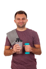 Young man holding a protein shake and a dumbbell