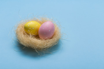Colorfull easter eggs in nest on green pastel color background with space.