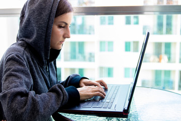 Woman Hacker programmer is working on computer in cyber security center filled with display screens