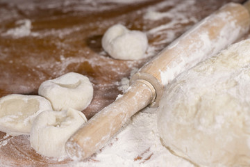 piece of dough, flour and rolling pin on the table