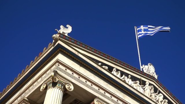 Slow Motion video from iconic neoclassic Academy of Athens facade with Greek flag waving slowly, Athens historic center, Attica, Greece        