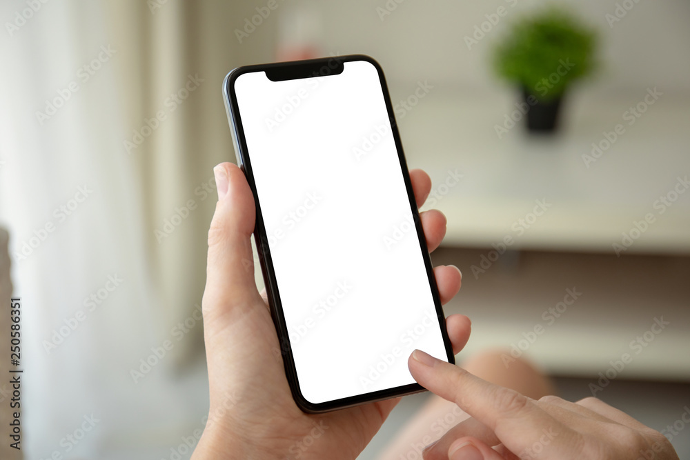 Wall mural female hands holding phone with isolated screen in room