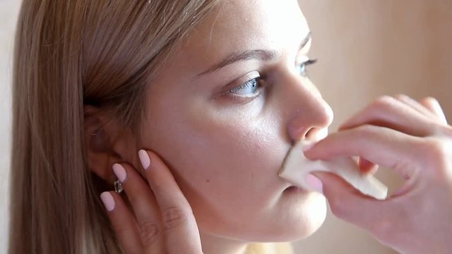 make-up artist hand wipes model's cheek