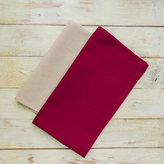Top view of cloth napkins of beige and burgundy colors in rustic white background.