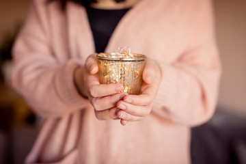 Fototapeta premium Junge Frau hält goldenes Glas mit Lichterkette