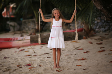 girl on the swing on the beach in white dress
