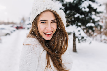 Spectacular long-haired woman laughing while posing on snow background. Outdoor close-up photo of...