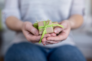 Schenken - Hände halten Geschenke in neutralen Farben verpackt in Recyclinpapier