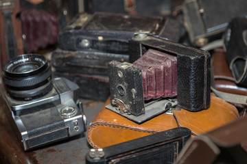 Antique Folding Camera with Bellows in a Pile of Old Cameras