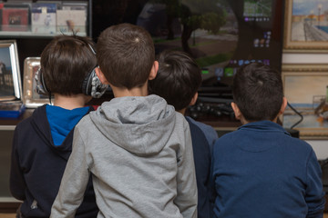 Fototapeta na wymiar Ten year old Children Seen from behind Playing Video games while sitting in front of the Television