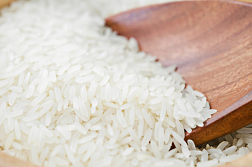 Raw white rice on wooden ladle.